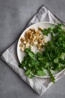 From above plate with assorted nuts and fresh herbs placed on napkin during baked sweet potato salad preparation — Stock Photo