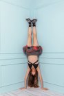 Teen Mädchen kopfüber in einer Ecke mit einem Modekleid auf türkisfarbenem Hintergrund — Stockfoto