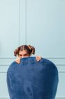 Дівчина-підліток прихована і щаслива в синьому кріслі на бірюзовому фоні — стокове фото