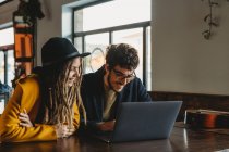 Stylish woman and man working on laptop in cafe — Stock Photo