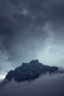 Dramatic mysterious rocky peak under gray clouds in foggy mist in Austria — Stock Photo