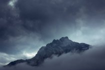 Drammatico misterioso picco roccioso sotto nuvole grigie nella nebbia nebbiosa in Austria — Foto stock
