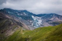 Green mountain ridge covered with snow on overcast day in Austria — Stock Photo