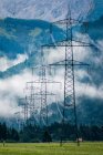 Промышленный ландшафт линий электропередач в туманных каменных горах под белыми облаками голубого цвета в Австрии — стоковое фото