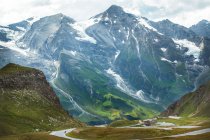 Grüner Bergrücken mit Schnee bedeckt am bewölkten Tag in Österreich — Stockfoto