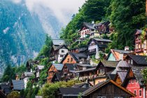Уютные домики маленького поселка, расположенного рядом с лесом на горном склоне в облачный день в Австрии — стоковое фото