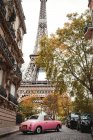 Von unten Eiffelturm und rosa Oldtimer in der Straße von Frankreich im Herbst — Stockfoto