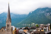 Laghetto pulito con acqua tranquilla e belle case di piccola città situata vicino cresta di montagna nella giornata nuvolosa in Austria — Foto stock