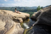 Mulher inspirada nadando na piscina pedregosa na cachoeira da montanha — Fotografia de Stock