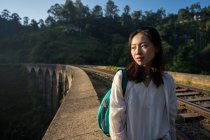 Asian woman looking away staying on old bridge with railway surrounded by green forest in Nine Arches Bridge,Ella, Sri Lanka — Stock Photo
