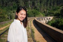 Nachdenkliche Asiatin läuft in alter Brücke entlang der Eisenbahn — Stockfoto