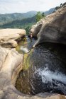 Inspirierte Frau schwimmt in steinernem Pool im Bergwasserfall — Stockfoto