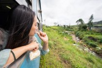 Отдыхающая азиатка садится на поезд вдоль зеленых растений — стоковое фото