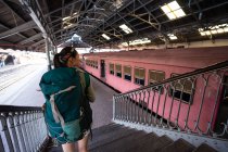 Mulher com mochila nas escadas na estação de trem — Fotografia de Stock