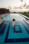 Viajante do sexo feminino em maiô descansando na piscina no resort — Fotografia de Stock