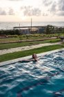 Женщина-путешественница в купальнике отдыхает в бассейне на курорте — стоковое фото
