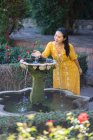 Asian woman touching fountain water in garden — Stock Photo