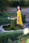 Asiatin steht neben Brunnenwasser im Garten — Stockfoto