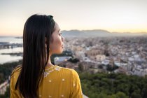 Asiático turista contra ciudad y puesta del sol cielo - foto de stock
