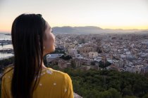 Asian tourist against city and sunset sky — Stock Photo