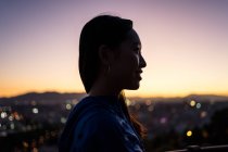 Щасливий азіатський турист проти міста і заходу сонця неба — стокове фото