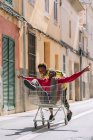 Feliz despreocupado jovens amigos afro-americanos em roupas casuais andando em torno de carrinho de compras na rua — Fotografia de Stock
