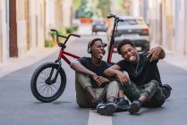 Fröhlicher, jugendlicher afroamerikanischer Teenager macht Selfie-Fotos auf dem Handy mit einem fröhlichen schwarzen Freund mit Kopfhörer — Stockfoto