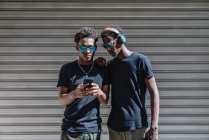 Fresco jovem Africano americanos adolescentes do sexo masculino em óculos de sol tirar foto com o telefone móvel, enquanto está em pé na luz do sol na rua — Fotografia de Stock