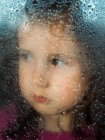 Menina atrás de vidro janela molhada — Fotografia de Stock
