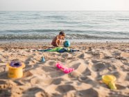 Niño jugando con arena en la playa - foto de stock