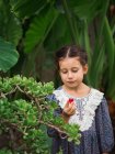 Chica escéptica comiendo fruta en el jardín - foto de stock