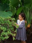 Chica escéptica comiendo fruta en el jardín - foto de stock