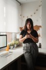Fokussierte Frau mit dunklen Haaren, die während ihres Aufenthalts auf dem Handy Nachrichten sendet — Stockfoto