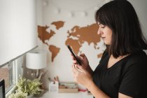 Focused woman with dark hair messaging on cellphone while being — Stock Photo