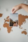 Anonymous woman holding picture in front of world map — Stock Photo