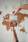 Anonymous woman holding picture in front of world map — Stock Photo