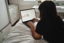 Focalisé jeune étudiante en utilisant un ordinateur portable sur le lit à la maison — Photo de stock