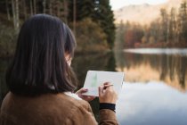 Mujer de pie junto al lago y dibujando en cuaderno - foto de stock