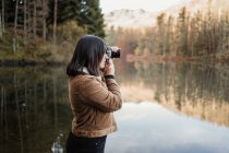 Woman taking photo at lakeside — Stock Photo