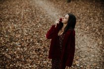 From above woman smiling and looking at camera with golden fallen leaves on blurred background — Stock Photo