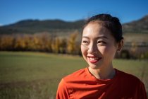 Sonriente mujer asiática caminando en campo campo - foto de stock