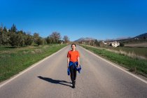 Smiling Asian woman walking on road in countryside — Stock Photo