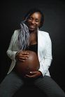 Afro-americana embarazada tocando vientre - foto de stock