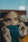 Страшная грустная молодая женщина с дредами, прислонившаяся к оконному стеклу и отворачивающаяся — стоковое фото