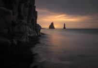 Знаменитий незвичайний чорний піщаний пляж і скелясте узбережжя на заході сонця в Ісландії. — стокове фото