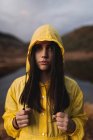 Traveler in yellow raincoat standing on shore of lake — Stock Photo