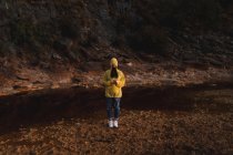 Женщина в жёлтом плаще прогуливается по природе — стоковое фото