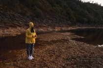Женщина в жёлтом плаще прогуливается по природе — стоковое фото