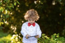 Curioso smartphone di navigazione bambino nel parco — Foto stock
