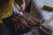 Cropped image of woman creating handmade dreamcatcher with long threads spending time in house — Stock Photo